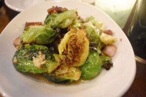 Brussels sprouts served with cured pork belly and wade in a puddle of honey white balsamic glaze.