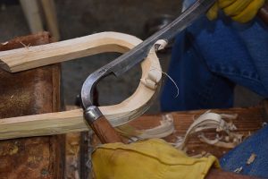 Jacques uses a drawknife to carve a lacrosse stick